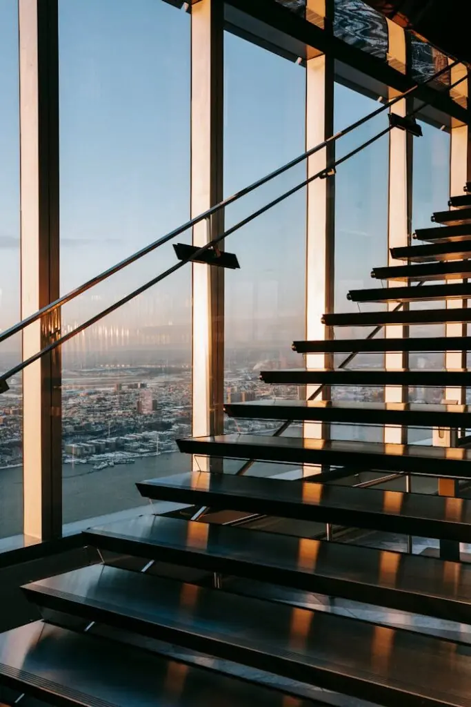 Sunlit staircase inside a modern glass office building overlooking the city